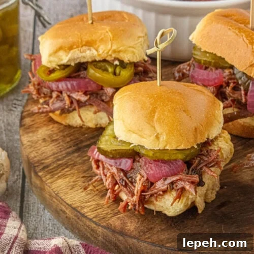 Slow cooker brisket sliders topped with pickles and pickled onions.