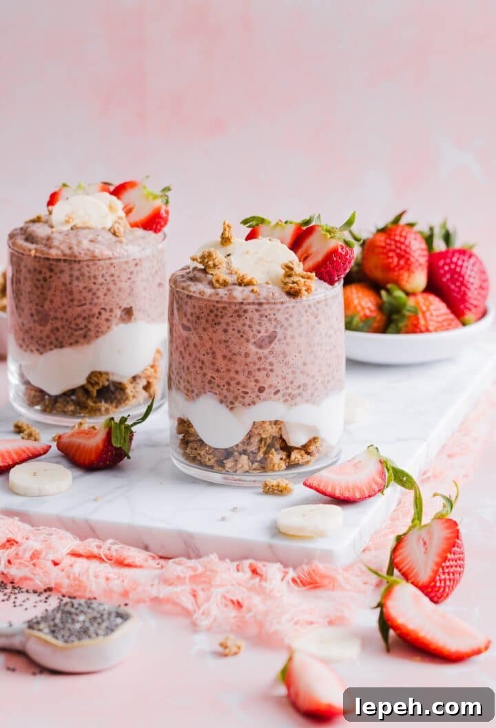 Two glass jars with strawberry banana chia pudding on a pink marble counter