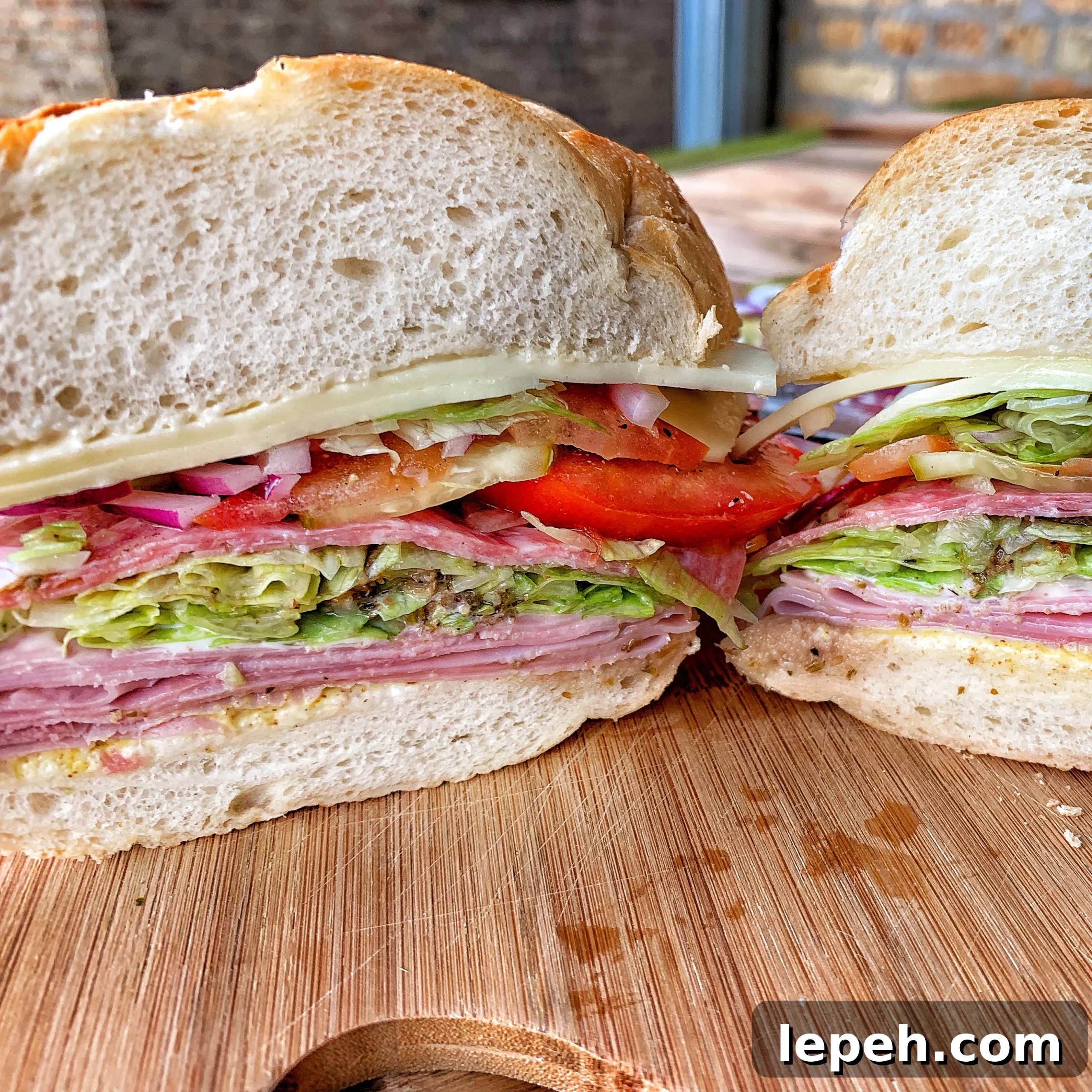 Picture of a sandwich cut in half showing all the layers of deli meat, cheese and veggies.