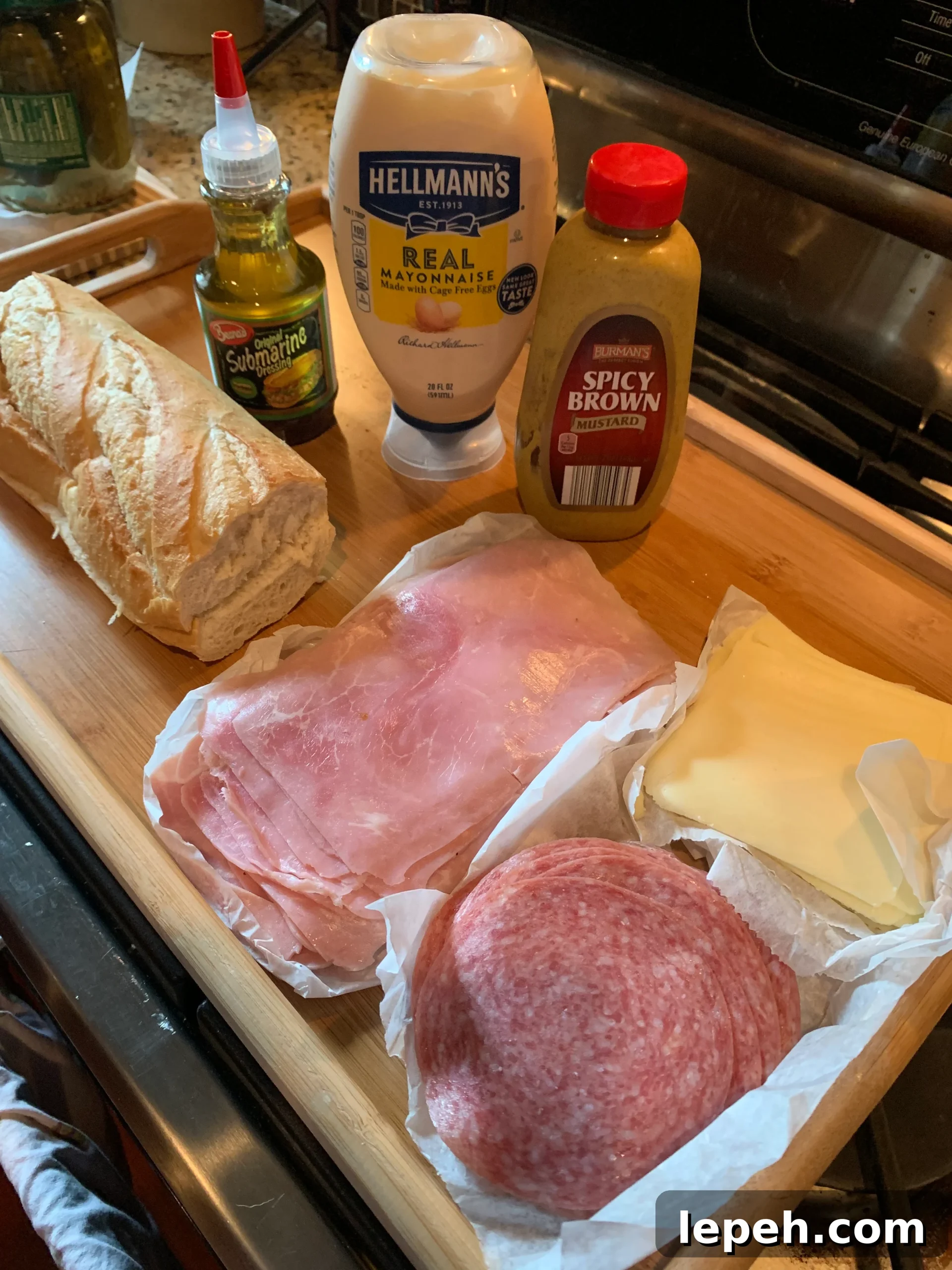 A photo of sandwich ingredients including French bread, Beano's sandwich dressing, mayo, spicy brown mustard, sliced ham, sliced salami, and sliced cheese