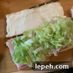 Shredded lettuce on ham on French bread sandwich
