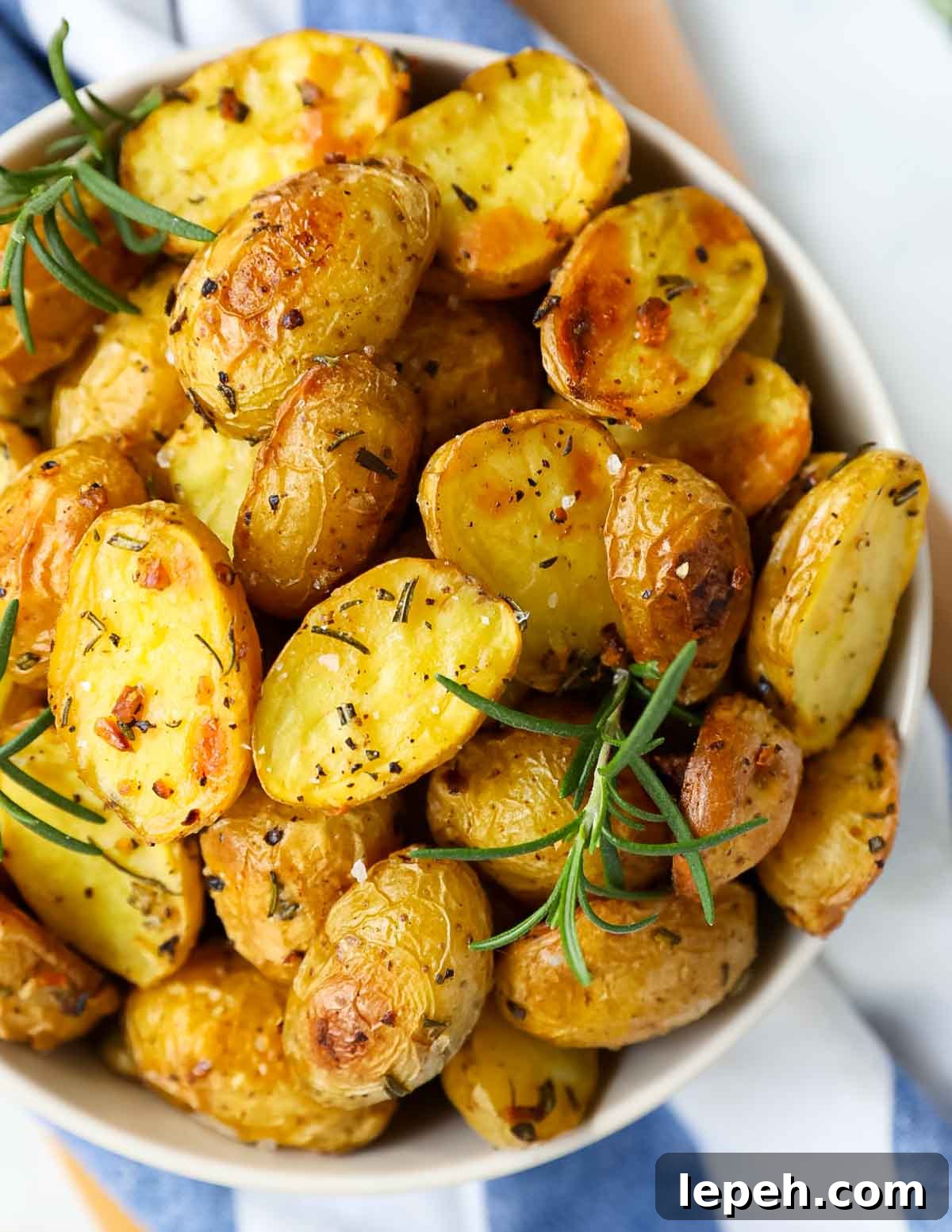 A close up image of sliced and roasted potatoes with seasoning on them inside of a bowl.
