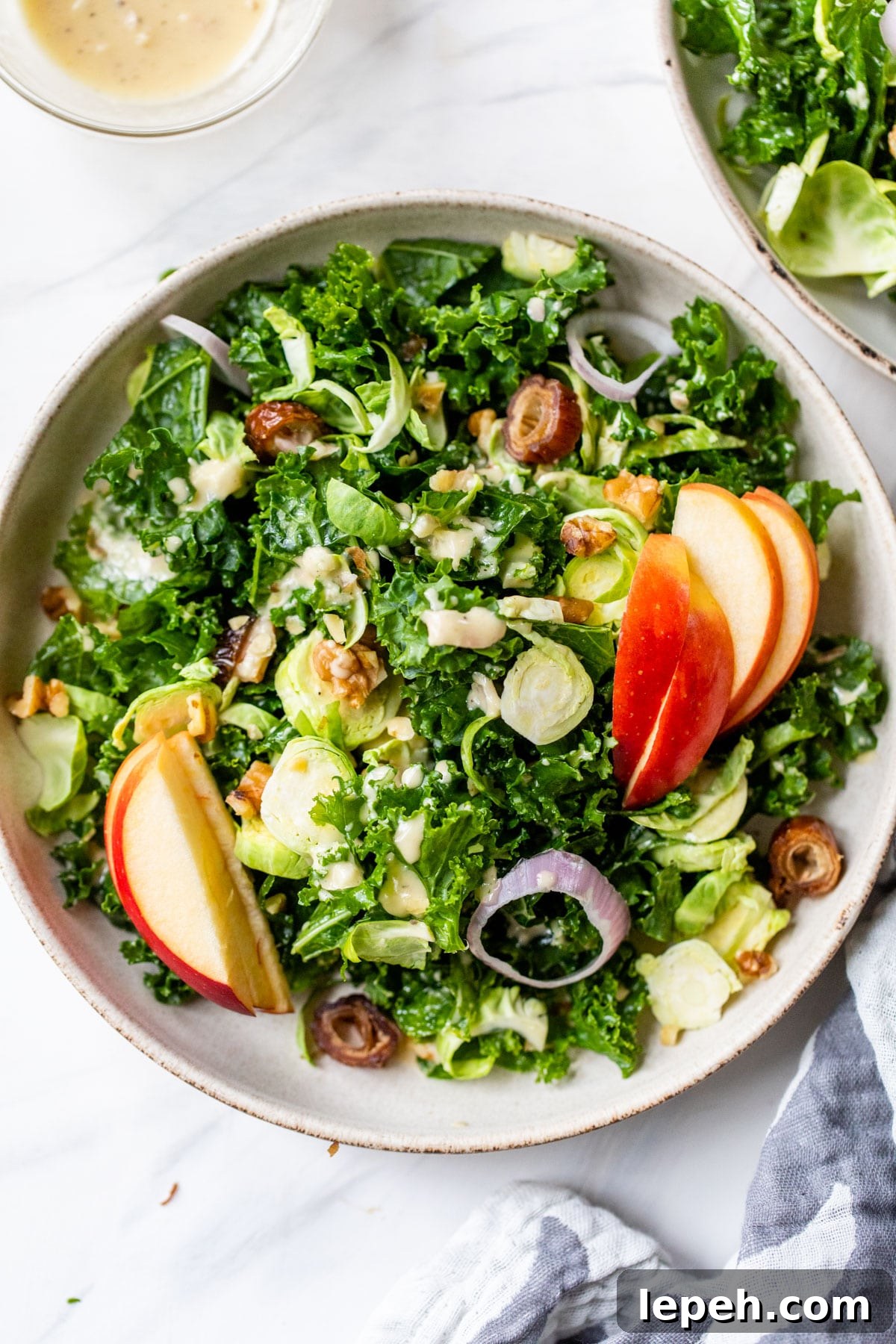 a bowl of kale salad with apples, brussels sprouts and shallots