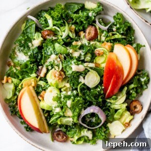 a bowl of kale salad with apples, brussels sprouts and shallots