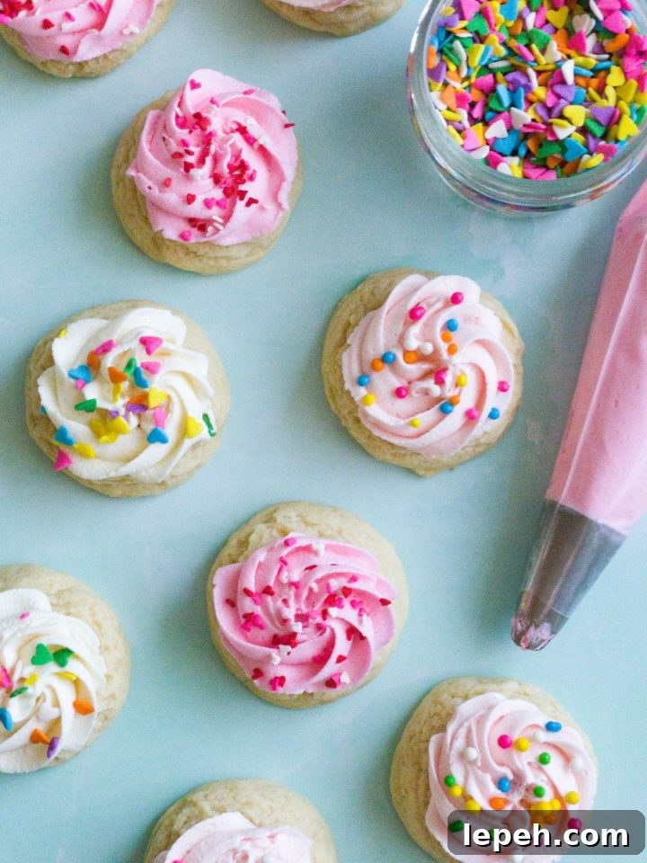 Several mini sugar cookies with a swirl of buttercream frosting and sprinkles
