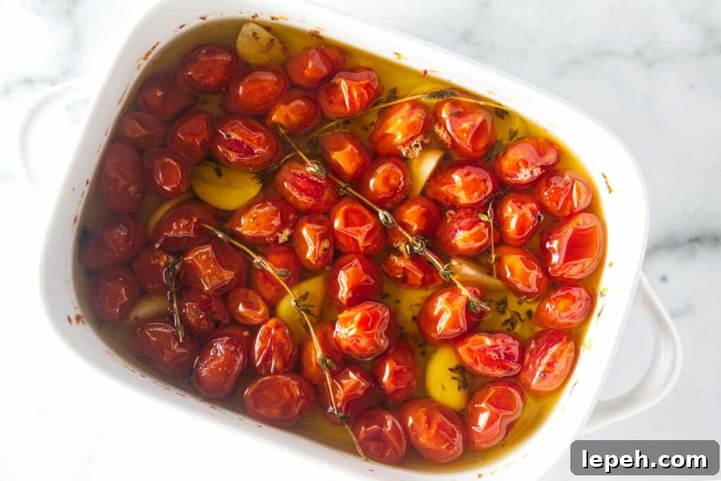 A dish of tomatoes, garlic and thyme sprigs, covered in olive oil.