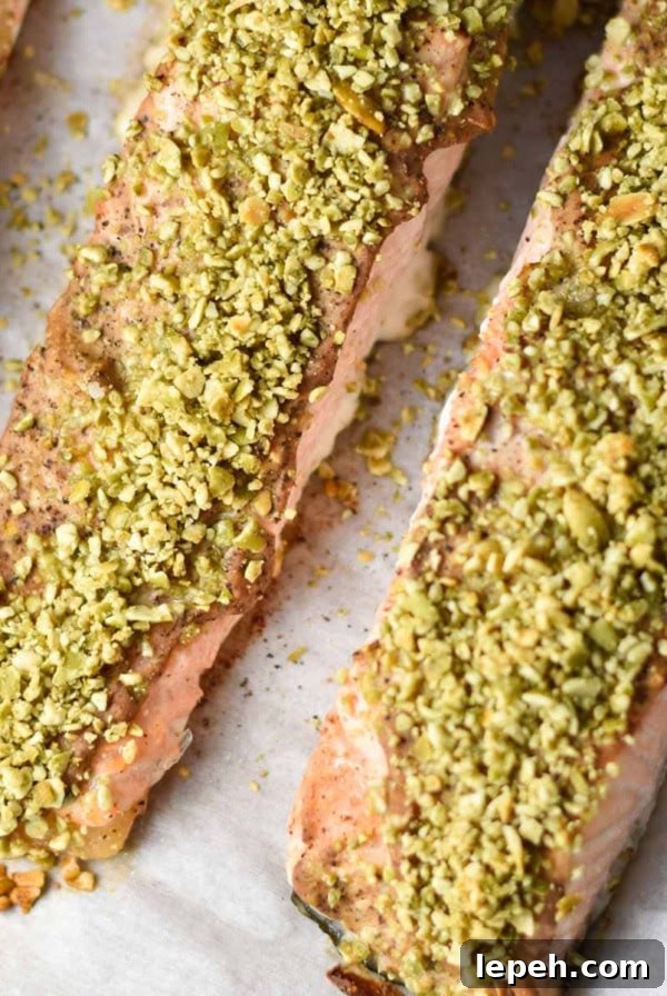 Three fillets of pepita crusted salmon on a baking sheet.