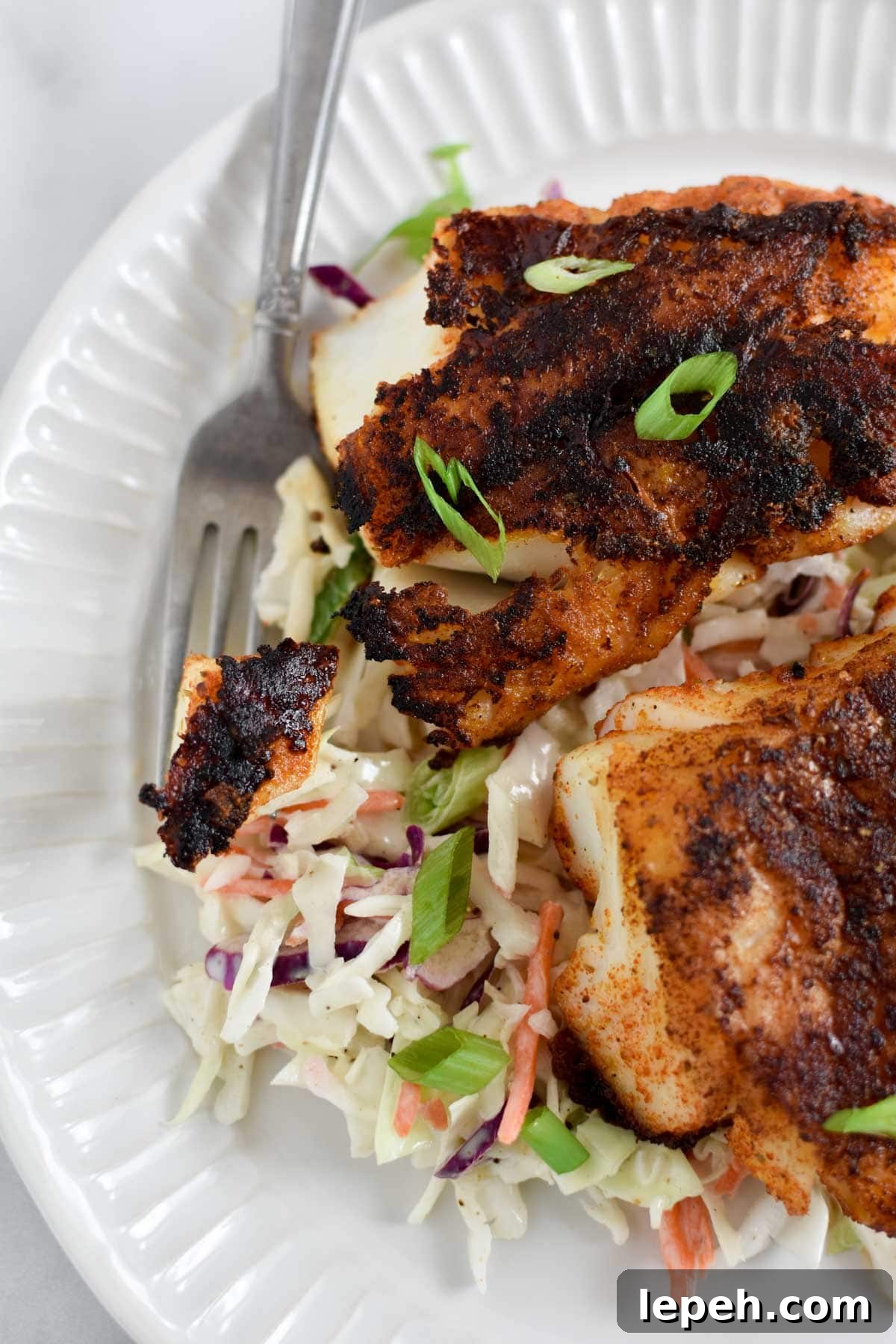 A fork holding a piece of pan seared cod