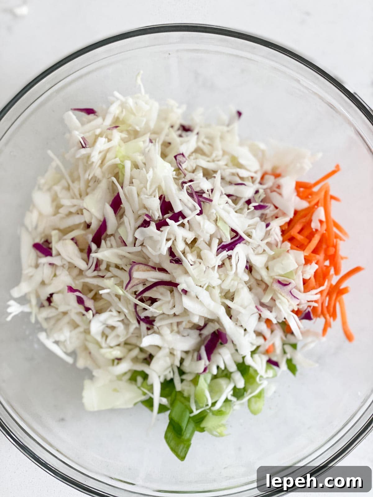 Cabbage, carrots, and green onion added to a coleslaw dressing mixture.