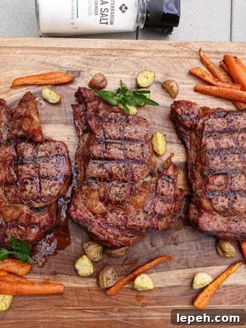 Three smoked steaks on cutting board with carrots and potatoes