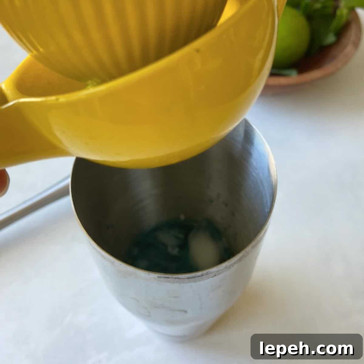Squeezing lime juice into shaker over mint.