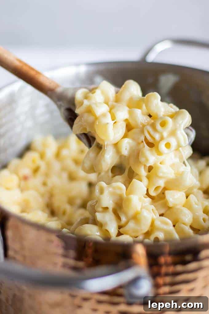 A pot of creamy mac and cheese with a spoon scooping