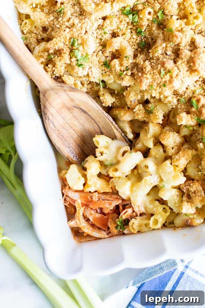 A close up of a pan of buffalo chicken mac n cheese showing the saucy chicken under the noodles.