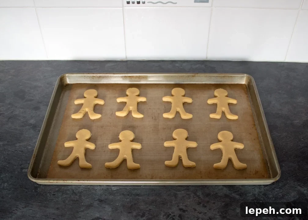 Gingerbread men on a lined baking tray on a kitchen worktop.
