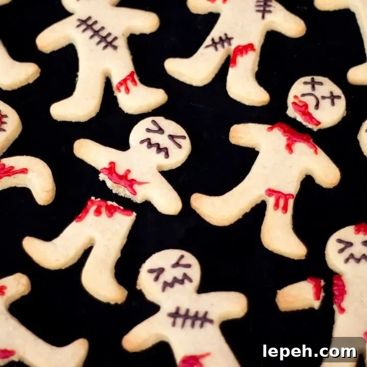 Flat lay view of lots of decorated ginger-dead men Halloween biscuits against a black background.