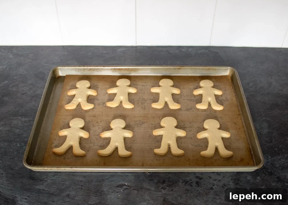 Baked gingerbread men on a lined baking tray on a kitchen worktop.
