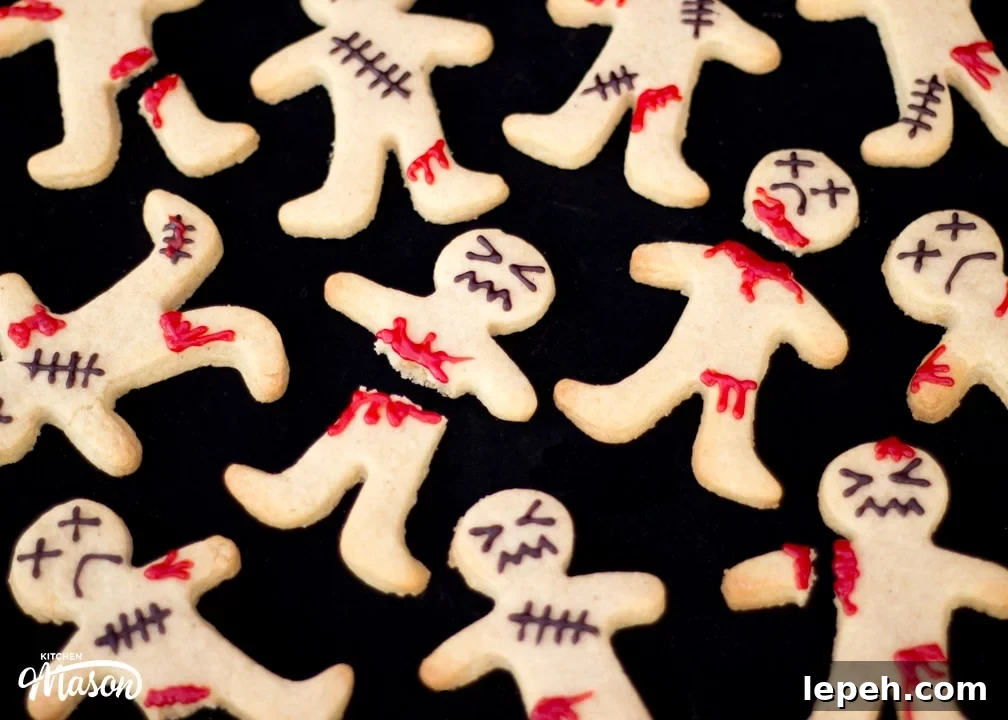 Flat lay view of lots of decorated ginger-dead men Halloween biscuits against a black background.