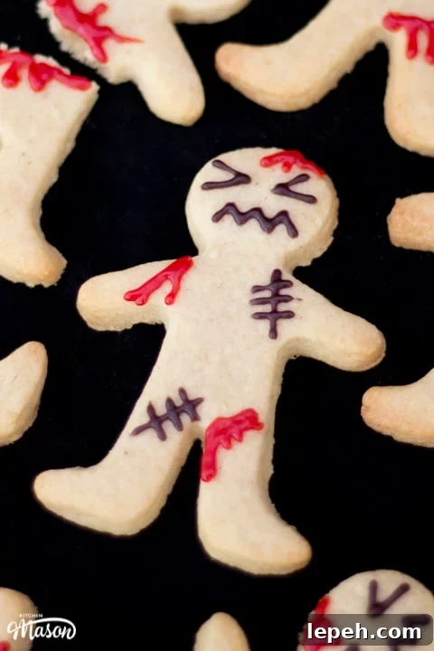 Close up flat lay view of a decorated ginger-dead man Halloween biscuits against a black background.
