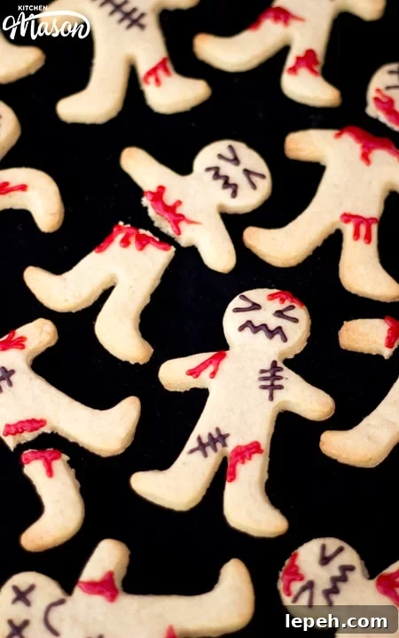 Flat lay view of lots of decorated ginger-dead men Halloween biscuits against a black background.