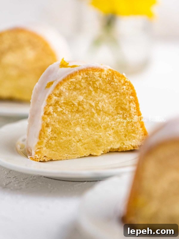 Small lemon cream cheese pound cake slice on a small dessert plate on white background.