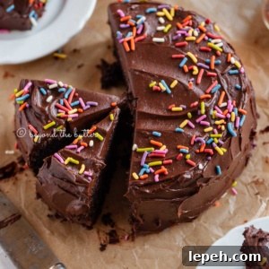 Angled image of sliced single layer chocolate cake on parchment paper with slices of cake on small dessert plates around it and a knife on parchment paper.