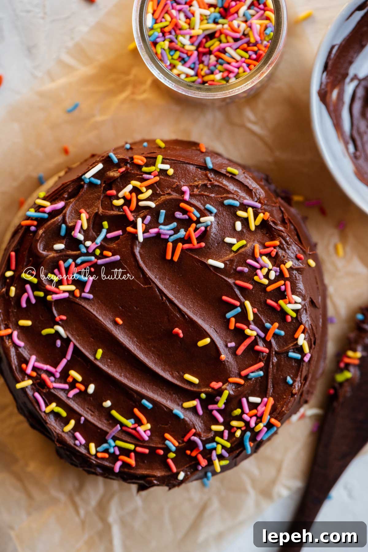 Overhead image of single layer chocolate cake with bowl of milk chocolate frosting | All Images © Beyond the Butter®
