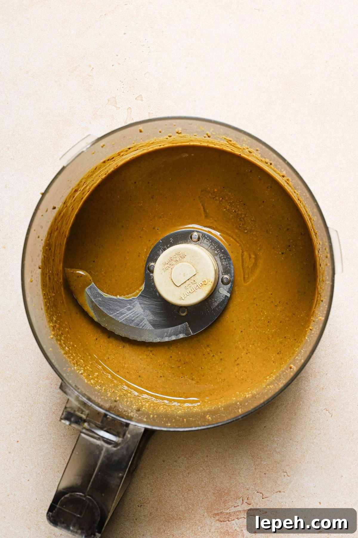 A food processor bowl with oily pistachio mixture.