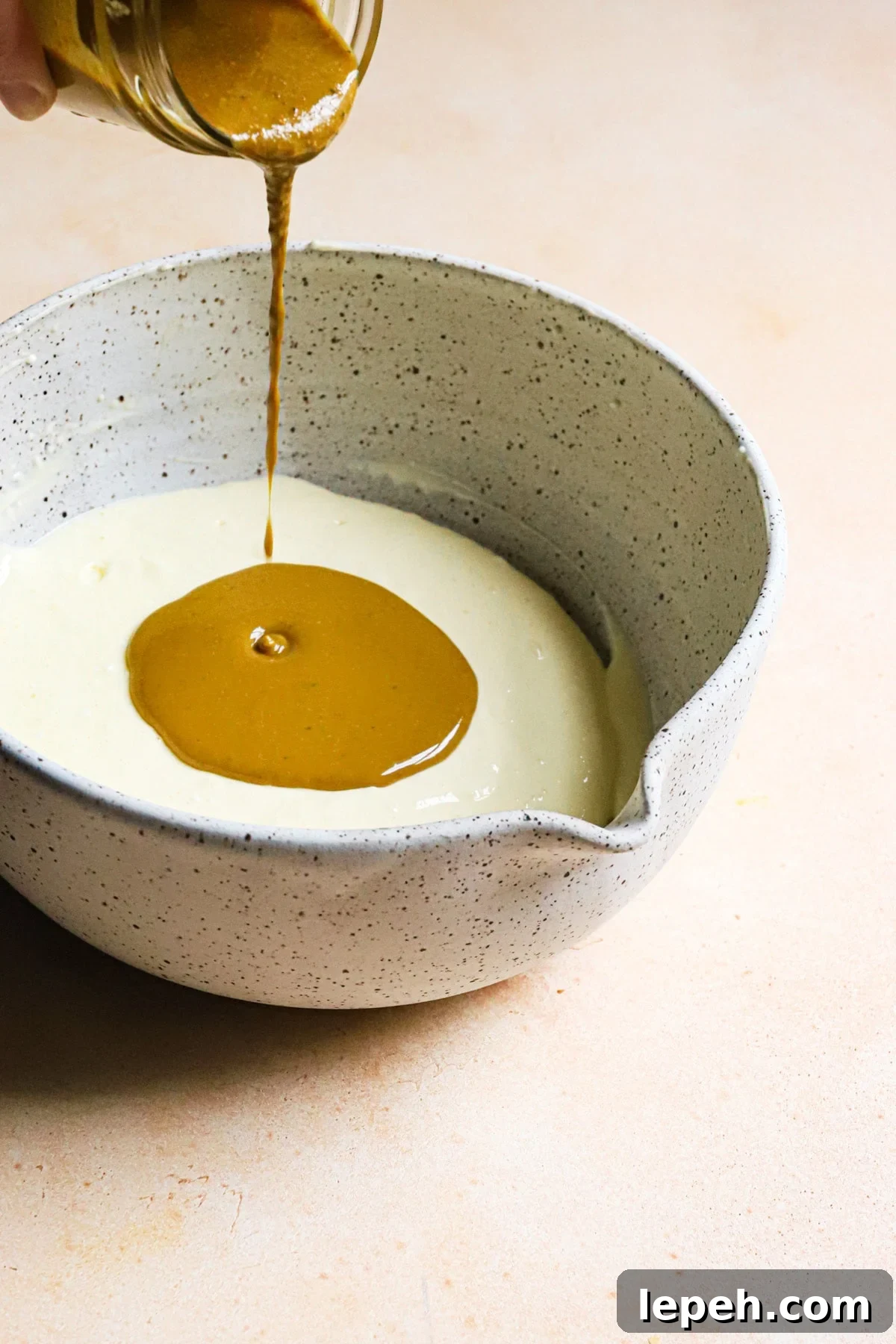 Pouring pistachio paste into cream cheese mixture.