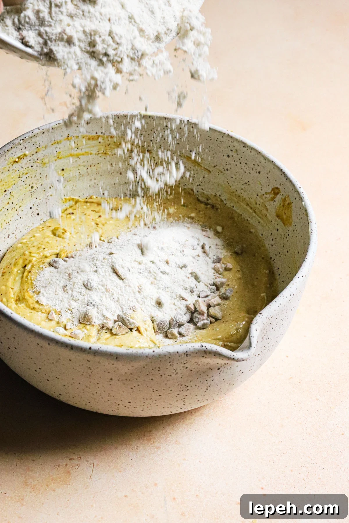 Adding flour to a bowl.