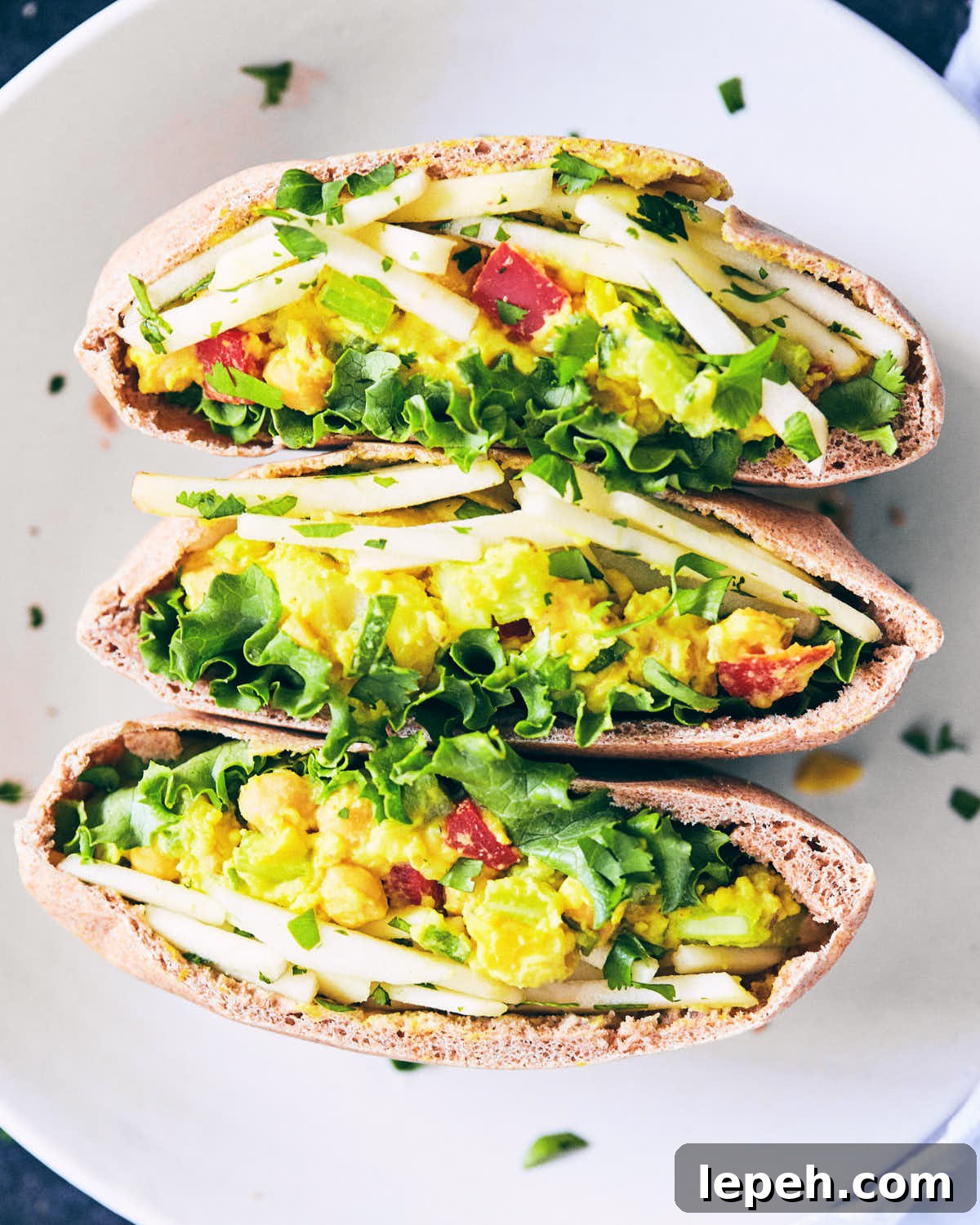 Curry chickpea salad stuffed pitas on a plate with apple slaw