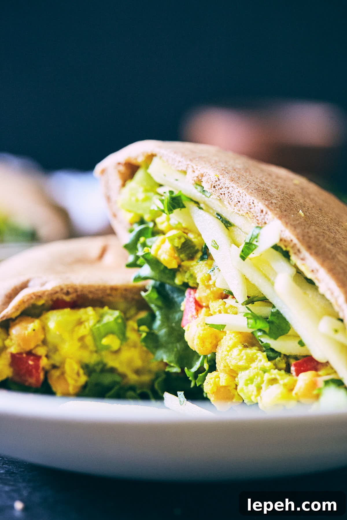 Side view of curry chickpeas salad stuffed pitas with apple slaw in a plate