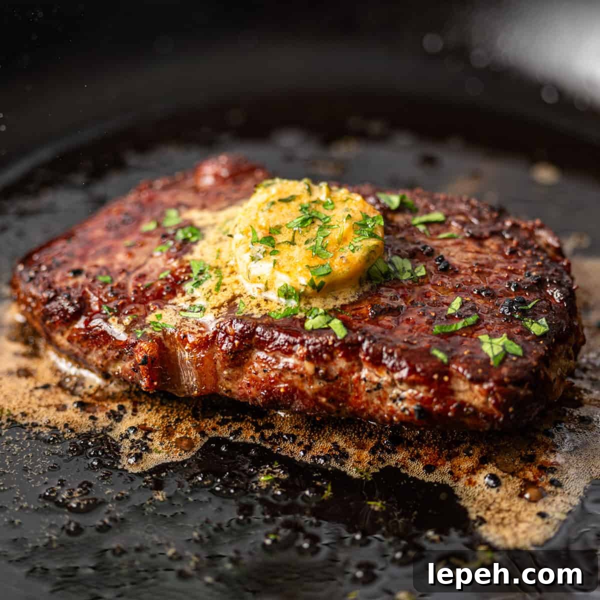 closeup: a steak cooking in a skillet with cowboy butter on top