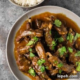 overhead photo: curried pork ribs covered in rich curry sauce on white dinner plate