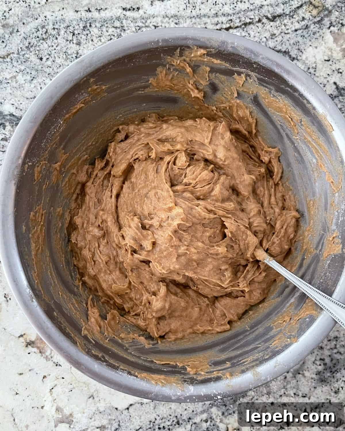 Mixing spice cake mix with mashed apple pie filling in mixing bowl.