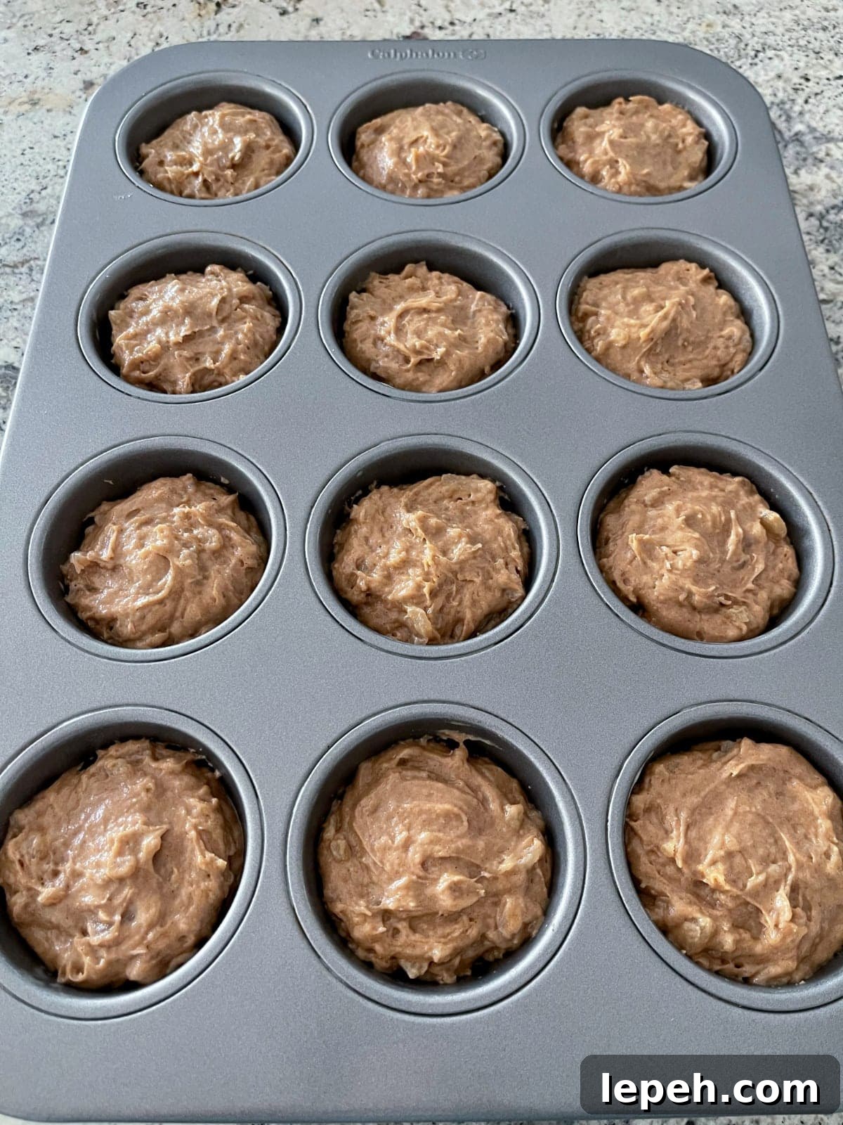 Unbaked apple spice cake mix cupcakes in muffin pan on granite counter.