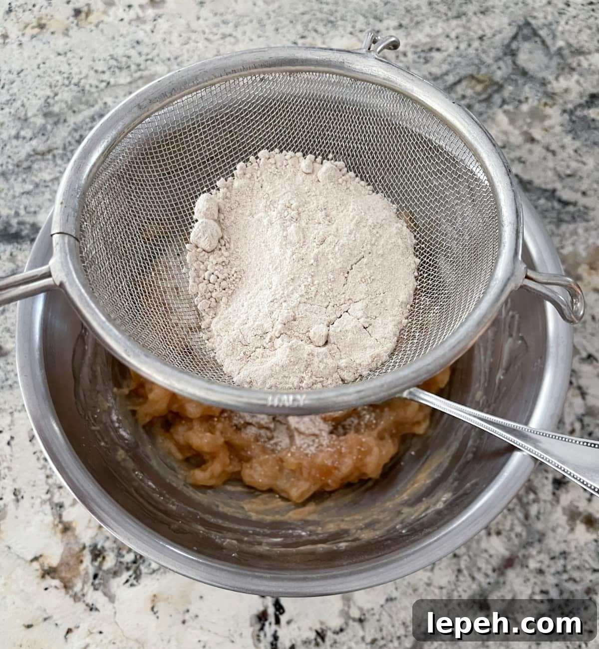 Sifting dry spice cake mix into mashed apple pie filling.