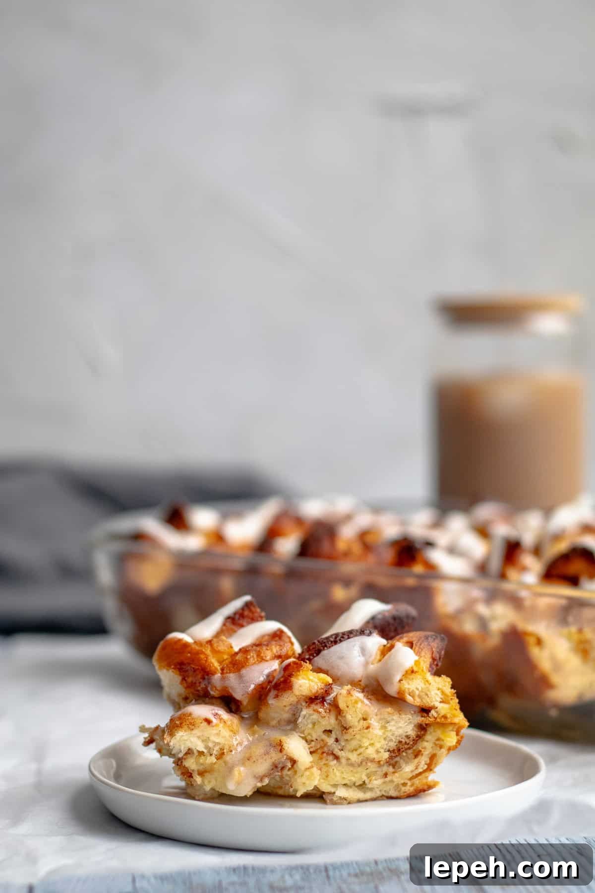 piece of breakfast casserole on a white plate with ice coffee in background