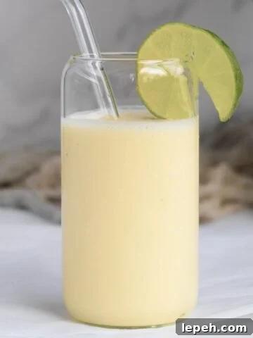 pina colada smoothie with a lime wedge in a glass