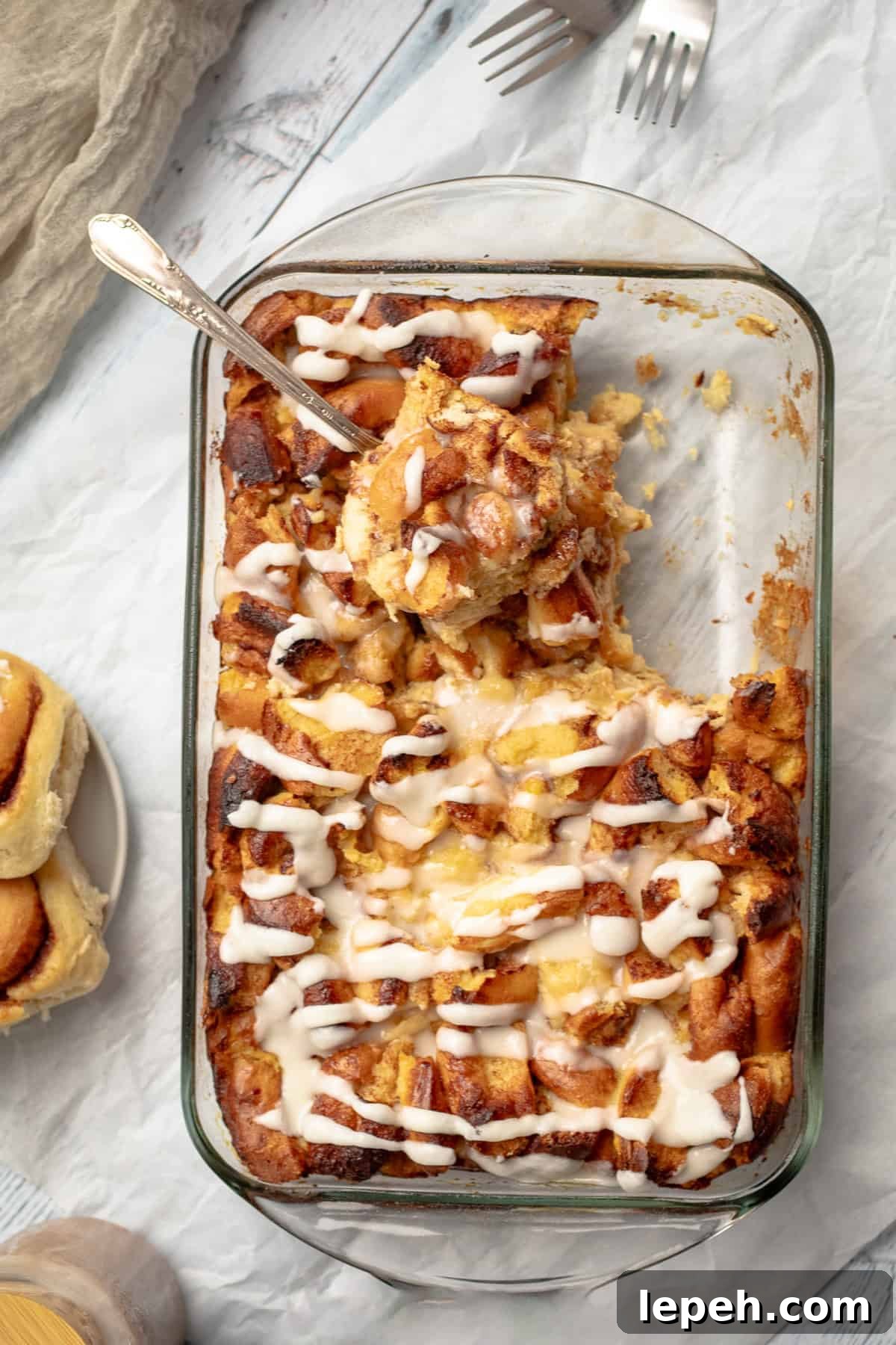 cinnamon roll breakfast casserold with icing and a scoop taking out of it