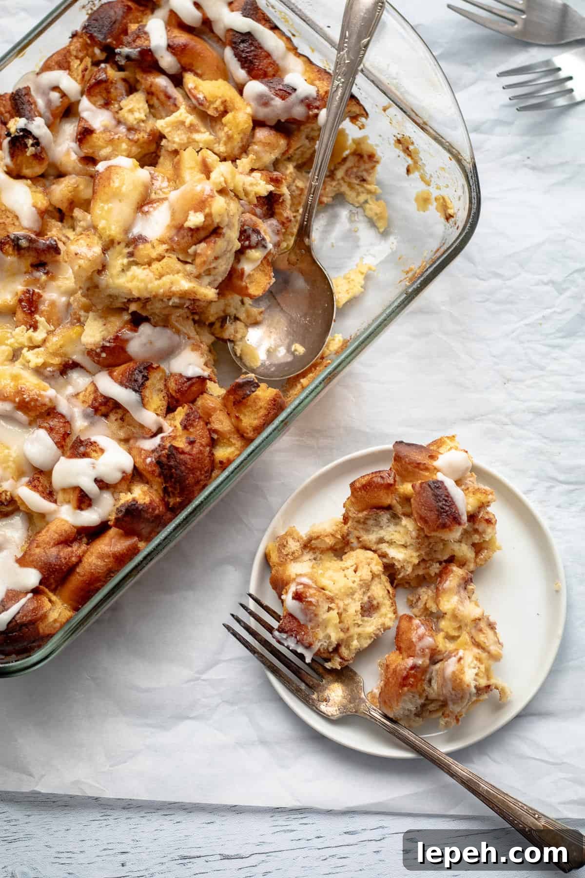 cinnamon roll breakfast casserole on a small plate with the remaining casserole in glass baking dish.