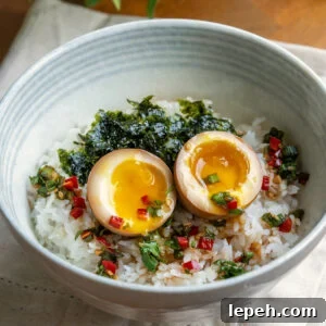 Jammy Korean marinated eggs (mayak eggs) in a bowl with rice.