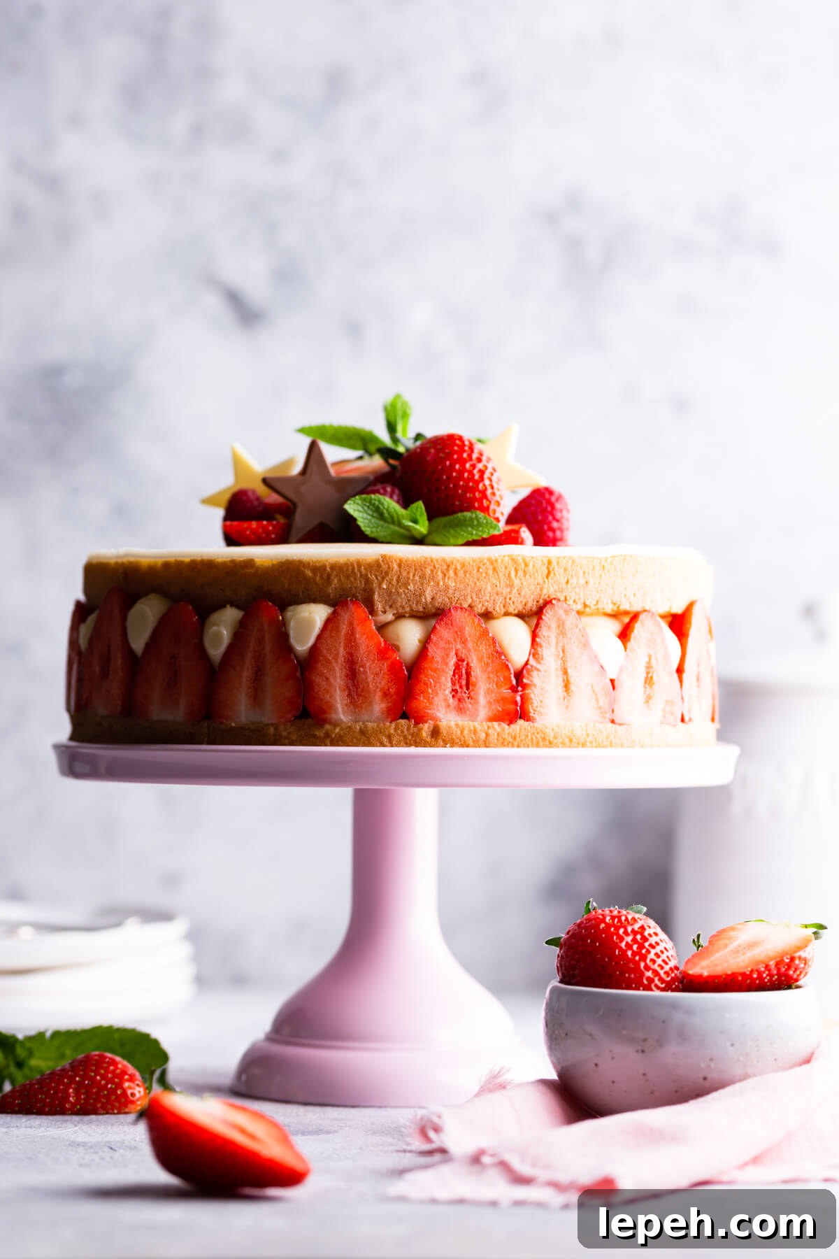 side close up of fraisier cake topped with fresh strawberries