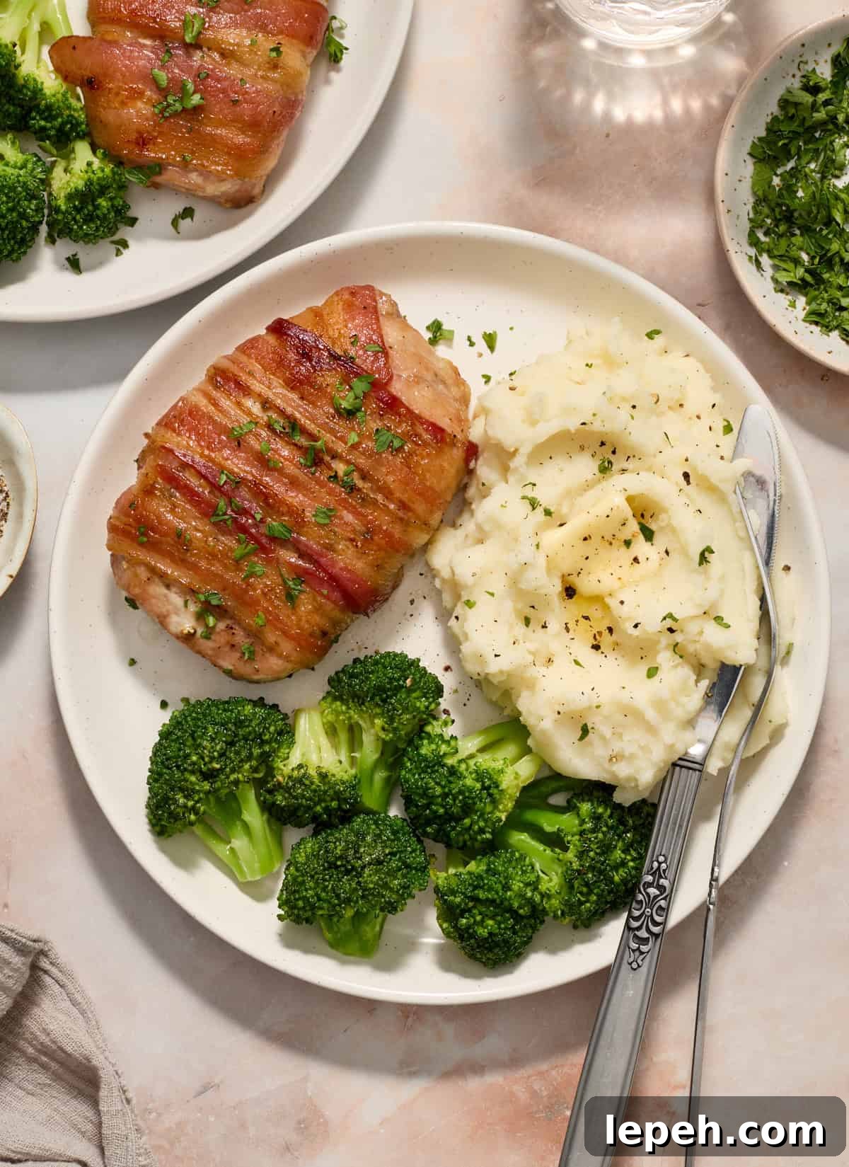 Overhead view of plate with bacon wrapped pork chop, broccoli and mashed potatoes.