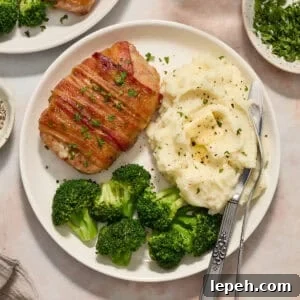 White plate with pork chop dinner including mashed potatoes and broccoli.