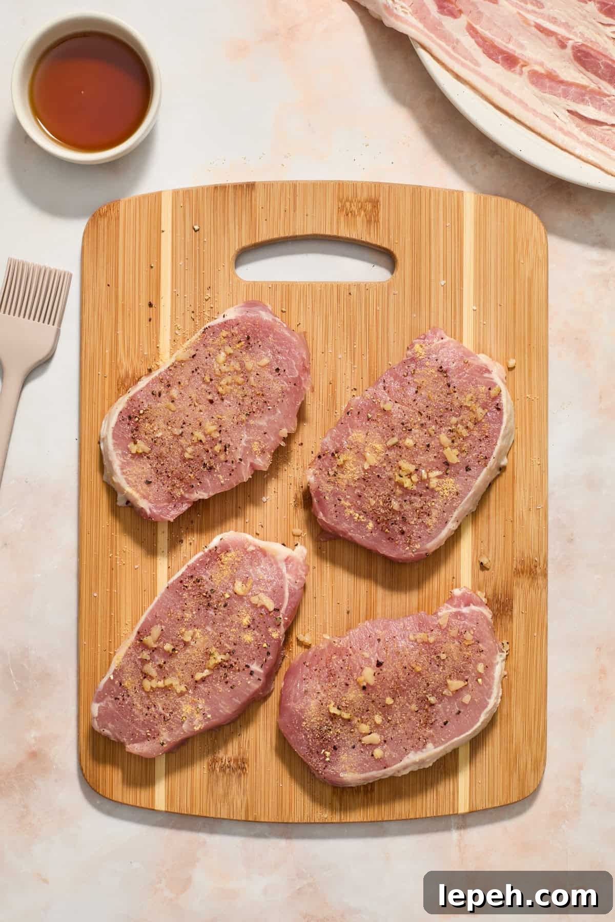 Seasoned pork chops on wood cutting board.
