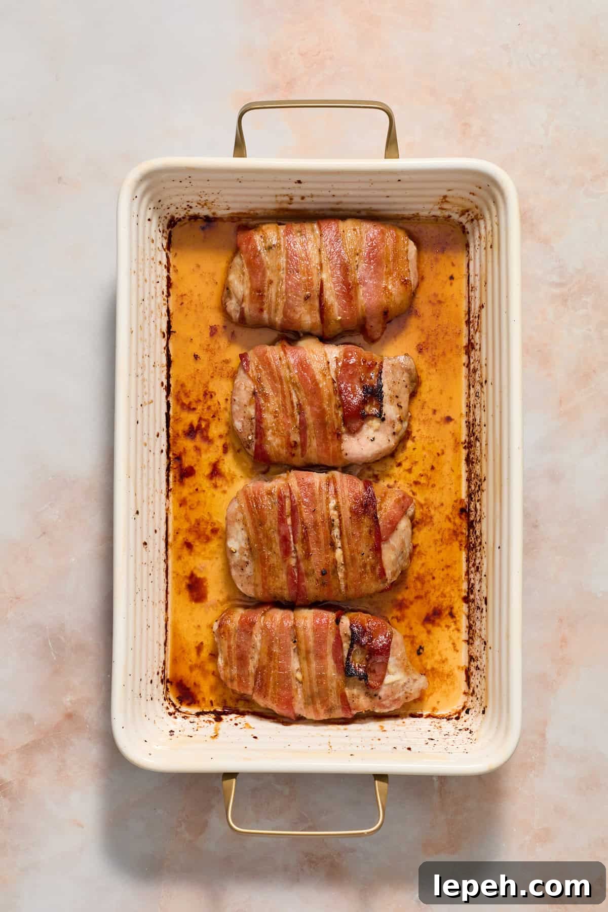Baked maple bacon wrapped pork chops in baking dish.