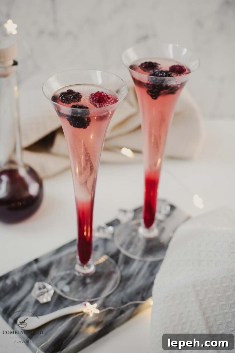 Chambord and Champagne Cocktail Recipe: Elegant Raspberry Sparkler 2 Champagne and chambord cocktail served in two champagne flutes. Garnished with berries.