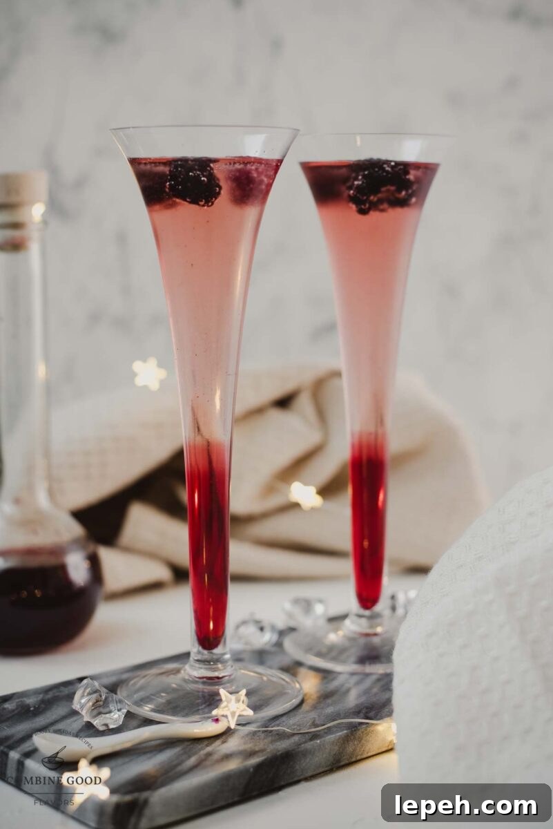 Chambord and Champagne Cocktail Recipe: Elegant Raspberry Sparkler 3 Champagne and chambord cocktail served in two champagne flutes. Garnished with berries.