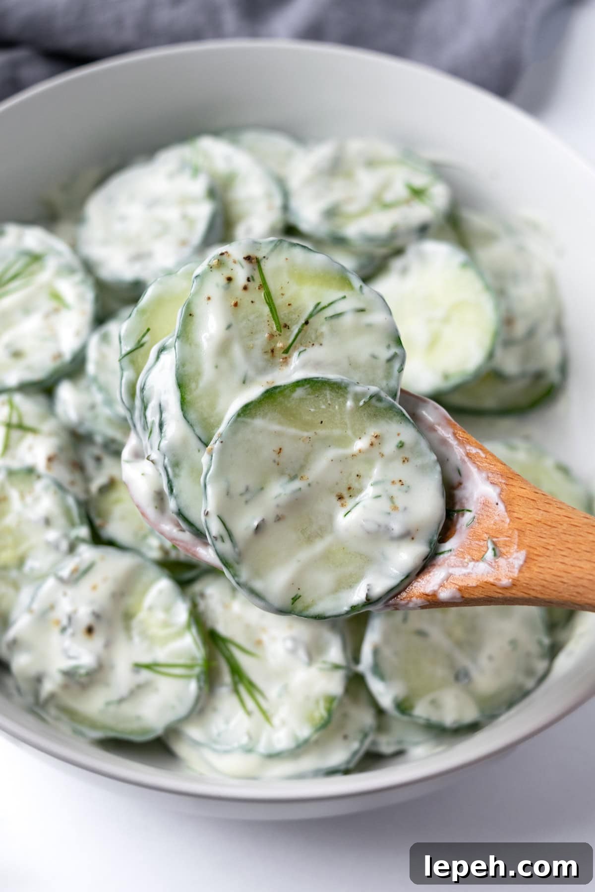 Creamy Cucumber Salad on a wooden spoon.